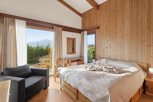 a bedroom with a bed and a chair and a window at Pirin Golf Villa in Bansko