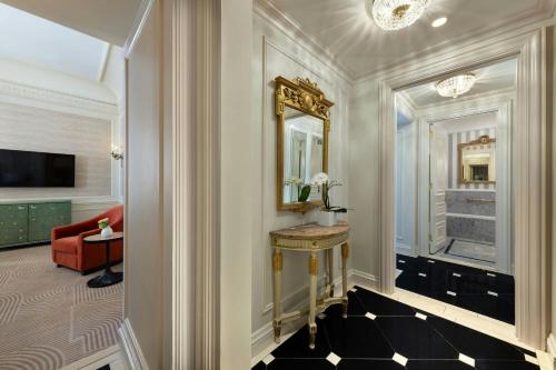 a hallway of a hotel with a mirror and a red chair at The St. Regis New York in New York