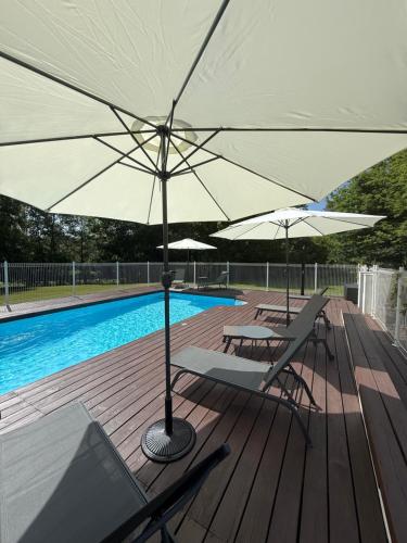 two chairs and umbrellas on a deck next to a pool at Les gîtes de la Joubertie in Salon