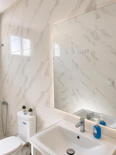 a white bathroom with a sink and a mirror at Appartement MIRAMAR in Martil