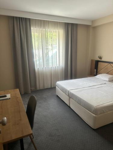 a bedroom with a bed and a desk and a window at Хотел Аква Варвара in Varvara