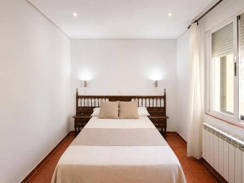 two beds in a room with white walls and a window at Hostal Bellas in Ávila