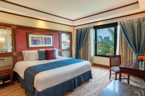 a hotel room with a bed and a desk and a window at Nairobi Serena Hotel in Nairobi