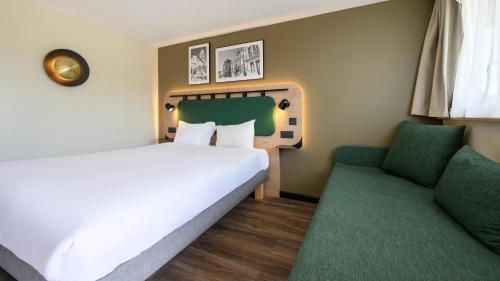 a bedroom with a white bed and a green chair at Campanile NATURE - Bollene in Bollène