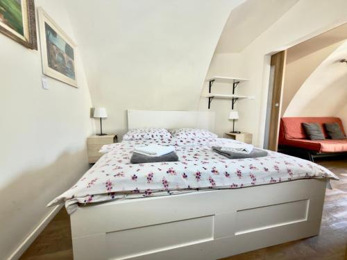 a white bed in a bedroom with a red chair at Apartmány u komína in Terezín