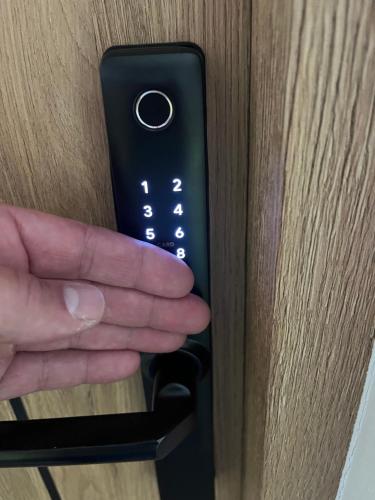a hand is holding a remote control in a door at Sara Apartament in Turek