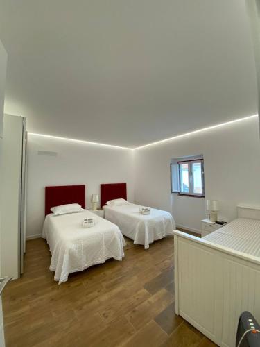 two beds in a room with white walls and wooden floors at Casa dos Manos in Barbacena