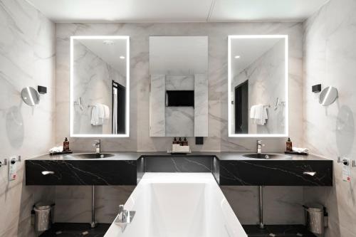a bathroom with two sinks and two mirrors at Thon Hotel Opera in Oslo
