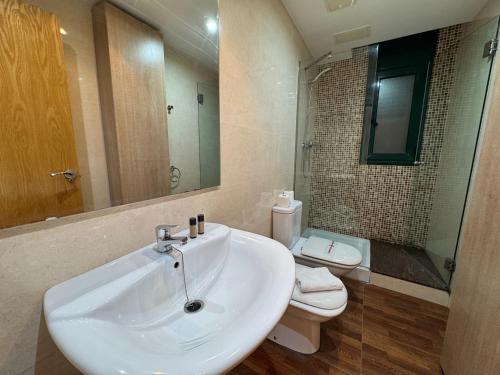 a bathroom with a sink and a toilet and a mirror at ACP Cambrils Puerto Apartamentos in Cambrils