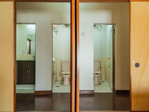 a bathroom with two glass doors and a toilet at Hokke Lumbini in Rummindei