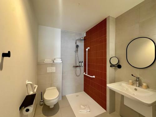 a bathroom with a toilet and a sink and a mirror at Hôtel des quatre saisons in Guérande
