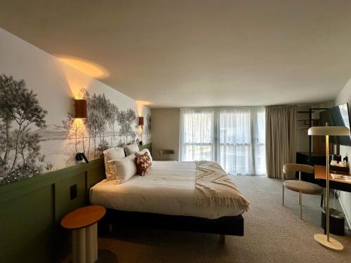 a hotel room with a bed and a desk and a room at Hôtel des quatre saisons in Guérande