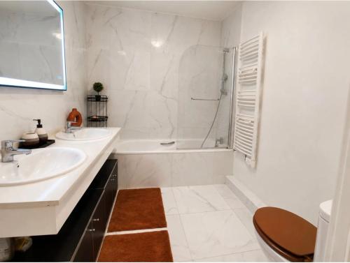 a white bathroom with a tub and a sink at Appartement luxury in Montpellier