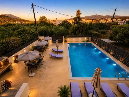 a swimming pool on a balcony with tables and umbrellas at Our Villa - Villa Rena in Rethymno