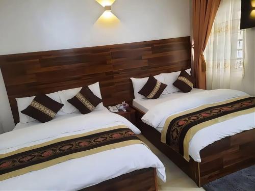 two beds in a hotel room with white and brown pillows at Nyansapo Eco Resort in Cape Coast