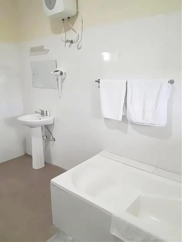 a white bathroom with a tub and a sink at Nyansapo Eco Resort in Cape Coast