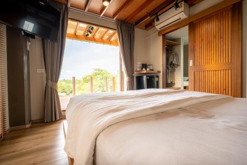 a bedroom with a large bed and a large window at Baanna Place in Ban Na