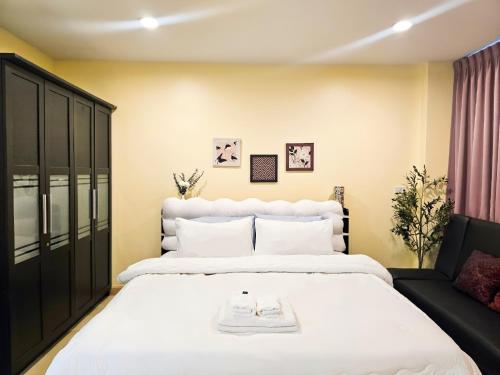a bedroom with a large white bed and a chair at The Beach Bangsaen Condo 327/30 in Ban Bang Saen (1)