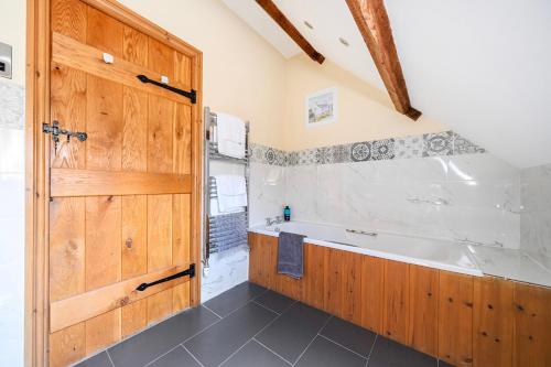 a bathroom with a wooden door and a bath tub at The Barn in Corwen