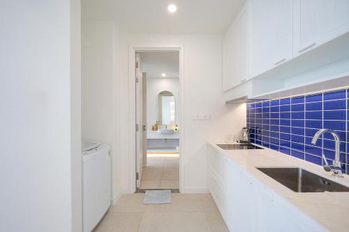 a white kitchen with a sink and blue tiles at Diamond Suite The Hill Phu Quoc in Phú Quốc