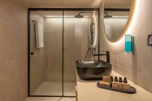 a bathroom with a shower and a counter with a sink at Indigo Suites Collection Adults Only in Hersonissos