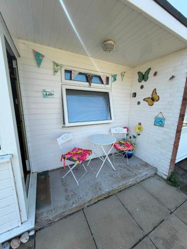 a patio with two chairs and a table and a window at Seabiscuit in Scratby