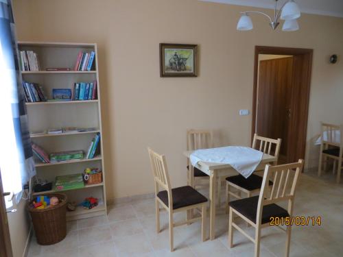 a room with a table and chairs and a book shelf at Kiserdő Vendégház in Rajka