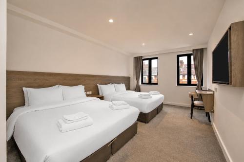 ein Hotelzimmer mit zwei Betten und einem Fernseher in der Unterkunft The Manor Park Hotel in London