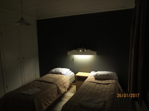 een donkere kamer met 2 bedden en een lamp bij Huoneistohotelli Jokikeskus in Kemi