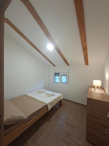 a white room with a bed and a night stand at Apartmani Suvodoli in Rvaši