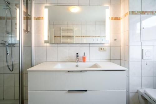 a white bathroom with a sink and a mirror at MueritzAusblick - Altstadtidyll mit Hafenblick in Waren