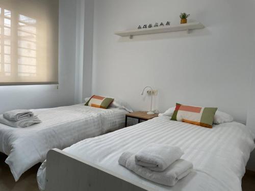 two beds in a white room with towels on them at Casa Yaye Ecija in Écija