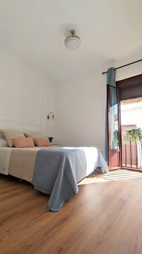 a white bedroom with a bed and a wooden floor at Casa Yaye Puerta Palma in Écija