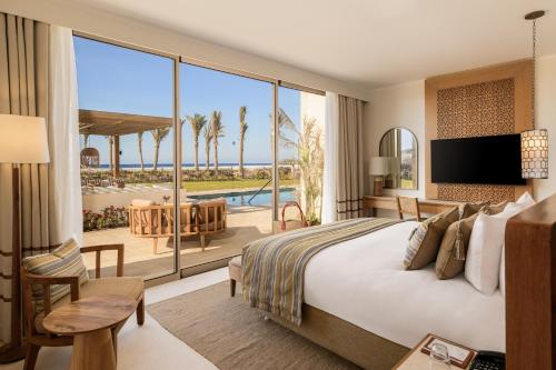 a hotel room with a bed and a view of a pool at Sakhra Hotel & Spa, Almaza Bay in Marsa Matruh