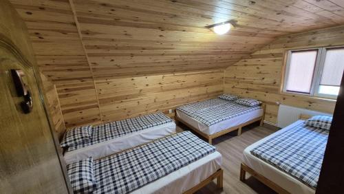 a room with three beds in a wooden cabin at Cabana Relax Time in Vălişoara