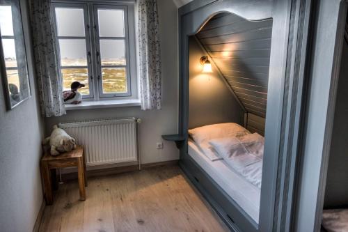 a small bedroom with a bed in a window at Reethuus am Fething in Langeneß