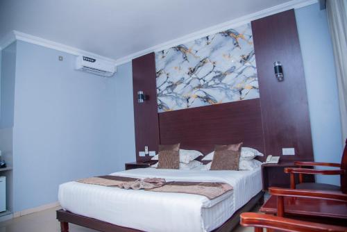 ein Schlafzimmer mit einem Bett und einem großen Gemälde an der Wand in der Unterkunft Mika Hotel Kabulonga in Lusaka