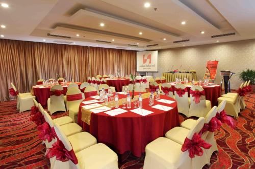 a banquet hall with red and white tables and chairs at Swiss-Belhotel Kendari in Kendari