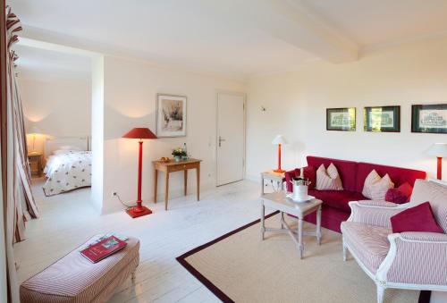 a living room with a red couch and a bed at Hotel & Restaurant Ole Liese in Panker