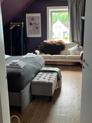 a bedroom with a bed and a couch and a window at Fjord House Hardanger in Grimo