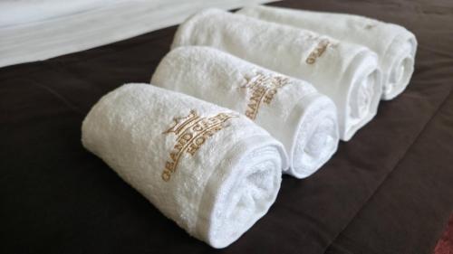 three rolls of white towels on a bed at Grand Capital Hotel in Tashkent