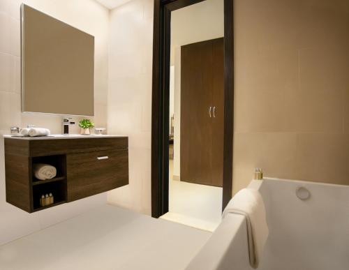 a bathroom with a tub and a sink and a mirror at Ascott Rafal Olaya Riyadh in Riyadh