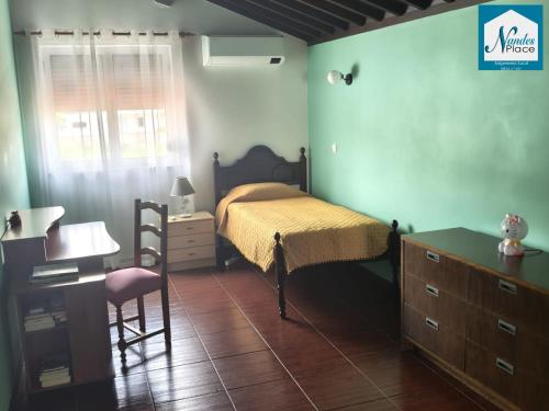 a bedroom with a bed and a desk and a chair at Nandes Place in Praia da Vitória