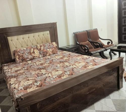 a bedroom with a large wooden bed and a chair at Canal Enclave, Canal Road West in Lahore