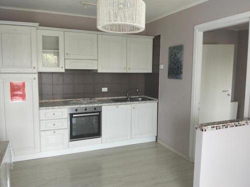 a kitchen with white cabinets and a sink at Villa Rosetta relax in Scrutto
