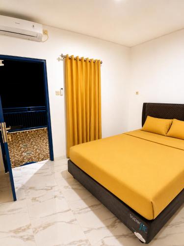 ein Schlafzimmer mit einem gelben Bett und einem Fernseher in der Unterkunft Moshi Moshi in Probolinggo