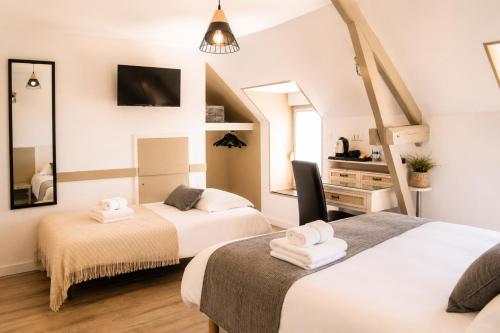a bedroom with two beds and a desk and a tv at Les Treize Assiettes - Baie du Mont-Saint-Michel in Le Val-Saint-Père