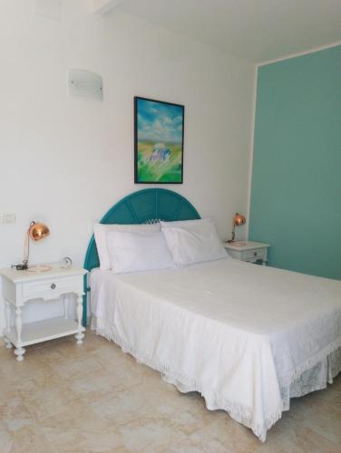 a bedroom with a white bed and two night stands at Finestre Sul Mare Salento - CasaVacanza in Punta Prosciutto