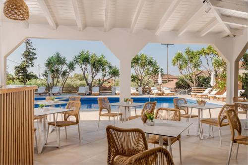 a restaurant with tables and chairs next to a pool at Noma Vasilikos in Vasilikos