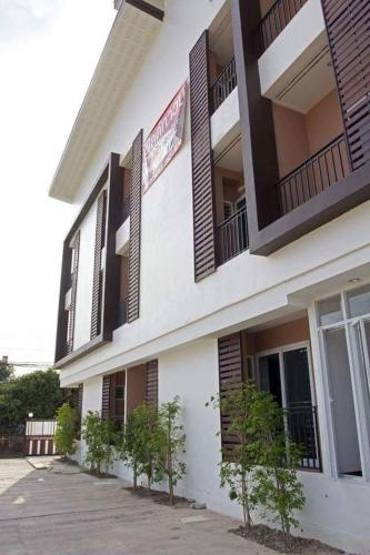 a white building with brown shuttered windows and plants at Field Town Apartment in Nakhon Nayok